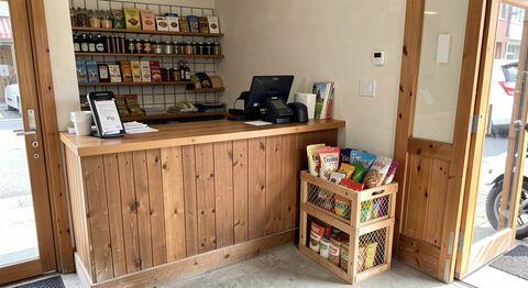The counter of a small independent shop with a card reader and a crate of goods by the door